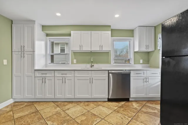 a kitchen with granite countertop white cabinets and stainless steel appliances