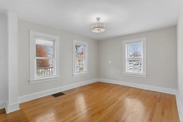 a view of an empty room with a window and wooden floor