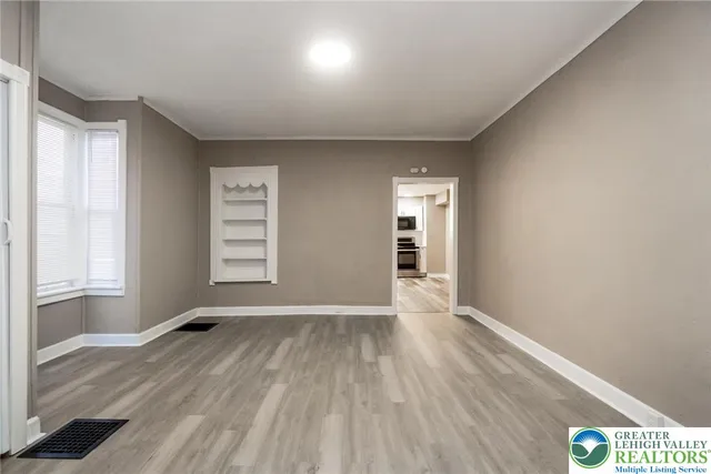 an empty room with wooden floor and windows