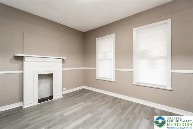 an empty room with wooden floor cabinet and windows