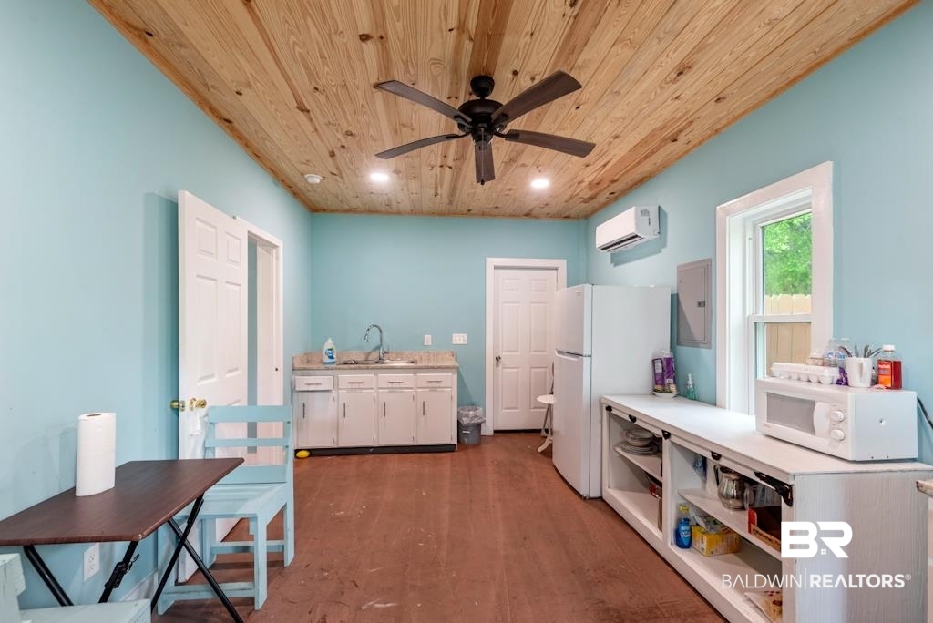 13742 Roberts Road Loxley, AL 36551 - Photo 5 of 18 Kitchen featuring light countertops, a wall unit AC, white appliances, wooden ceiling, and wood finished floors