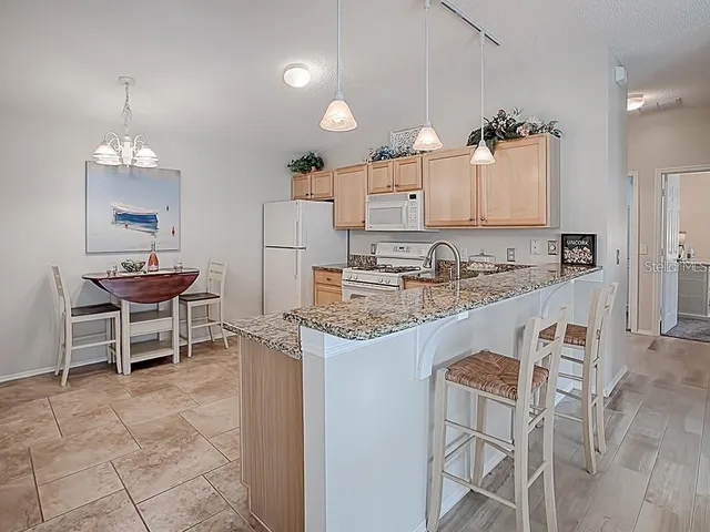 a kitchen with kitchen island granite countertop a sink and a refrigerator