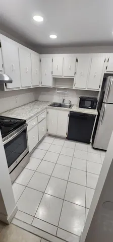 a kitchen with granite countertop white cabinets and white appliances
