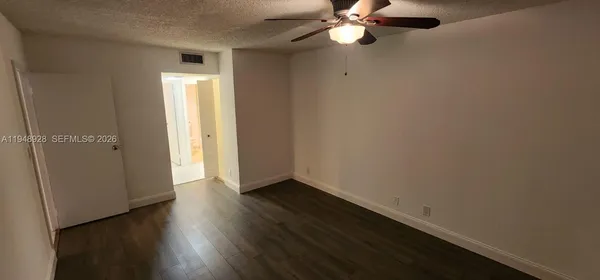 an empty room with wooden floor cabinet and windows