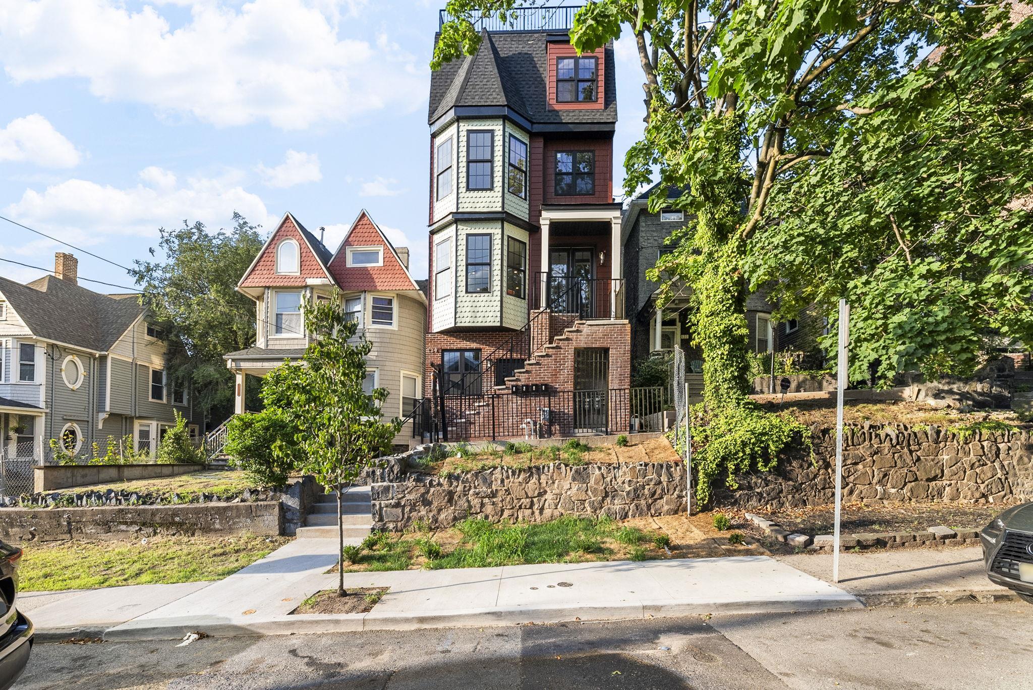124 Glenwood Avenue Jersey City, NJ 07306 - Photo 2 of 42 a front view of a house with a garden and tree