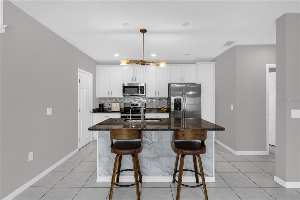 3470 Beau Road Kissimmee, FL 34746 - Photo 11 of 40 a kitchen with stainless steel appliances a refrigerator a stove a sink cabinets and a dining table