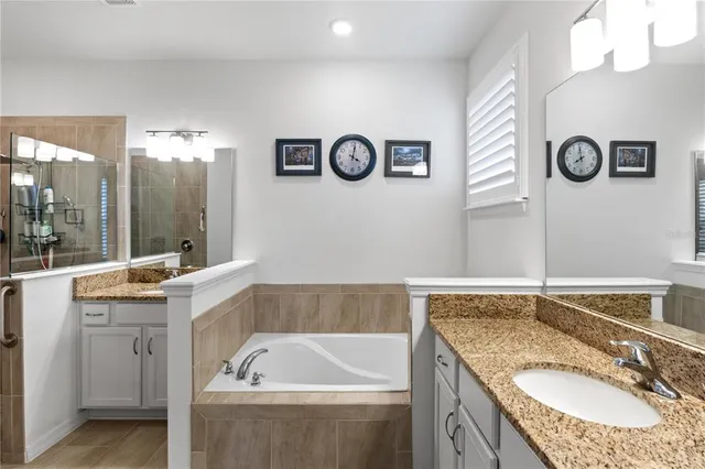 a bathroom with a granite countertop tub sink and mirror