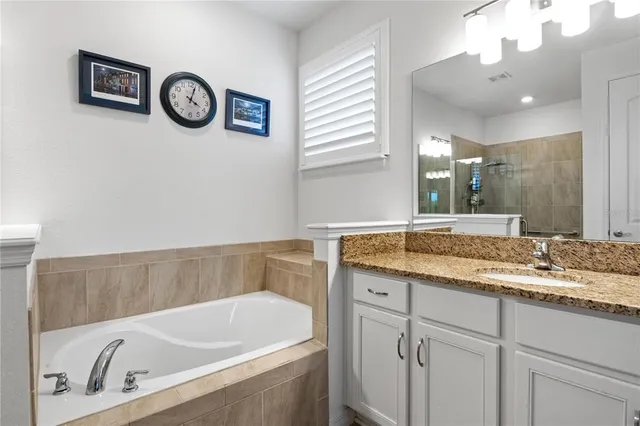 a bathroom with a granite countertop sink and a bathtub