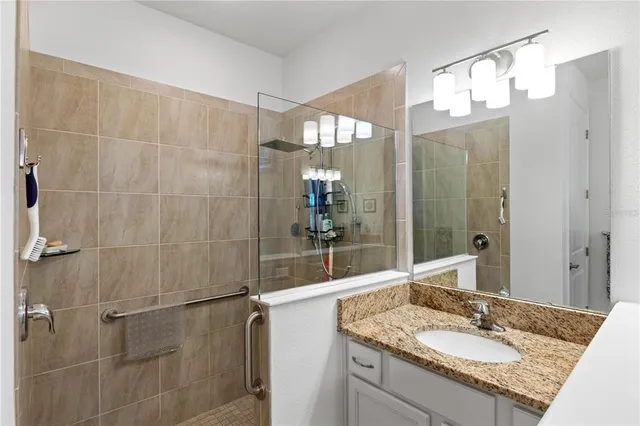 a bathroom with a granite countertop sink a mirror and a shower