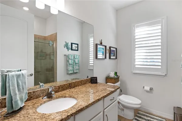 a bathroom with a granite countertop sink toilet and mirror