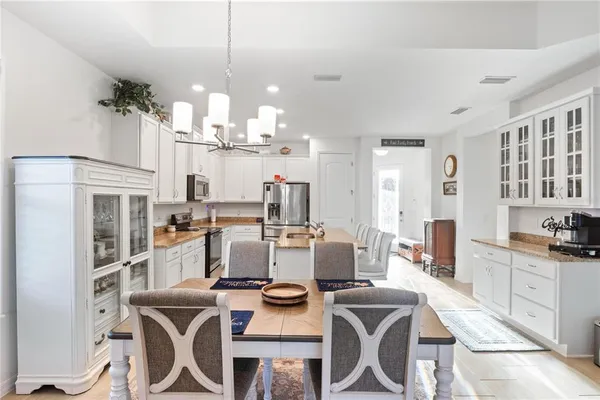 a view of a dining room with furniture a kitchen and chandelier