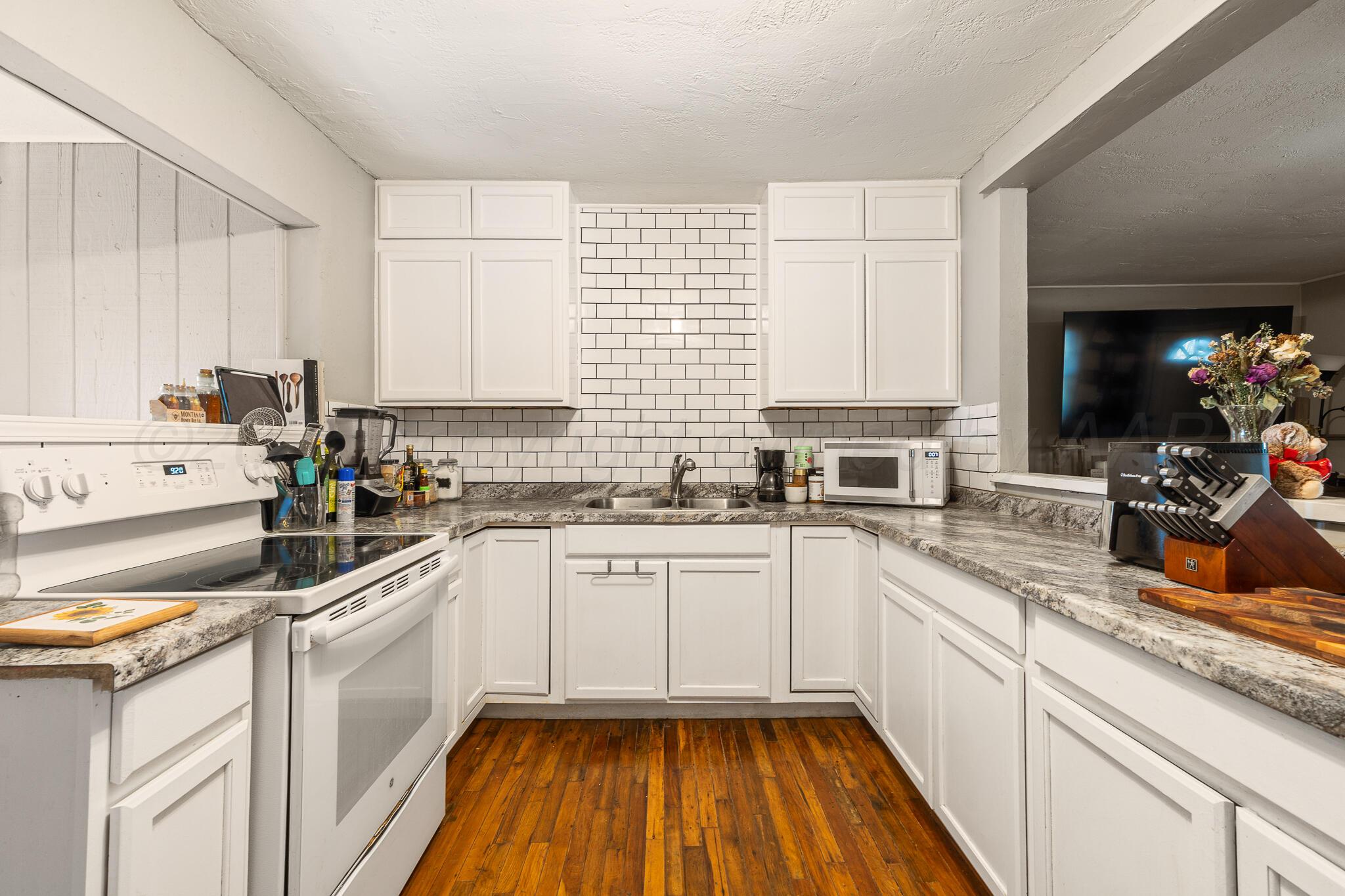 4607 Parker Street Amarillo, TX 79110 - Photo 5 of 11 a kitchen with a sink dishwasher a stove a microwave and cabinets
