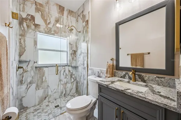 a bathroom with a granite countertop sink toilet and shower