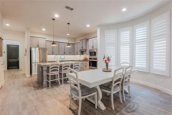 a kitchen with stainless steel appliances kitchen island granite countertop a dining table chairs and refrigerator
