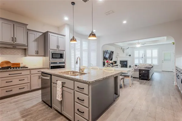 a kitchen with stainless steel appliances granite countertop a sink dishwasher a stove and a dining table with wooden floor