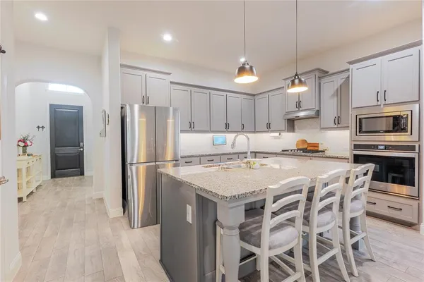 a kitchen with stainless steel appliances a refrigerator a stove a sink and chairs
