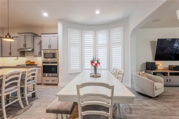 a living room with stainless steel appliances furniture a flat screen tv and kitchen view