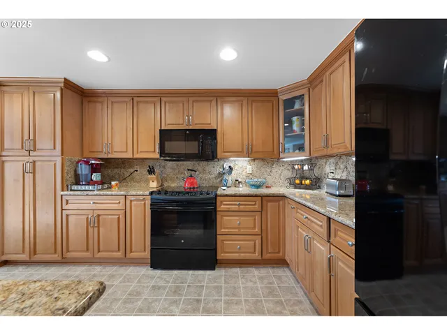 a kitchen with granite countertop a refrigerator stove top oven and sink