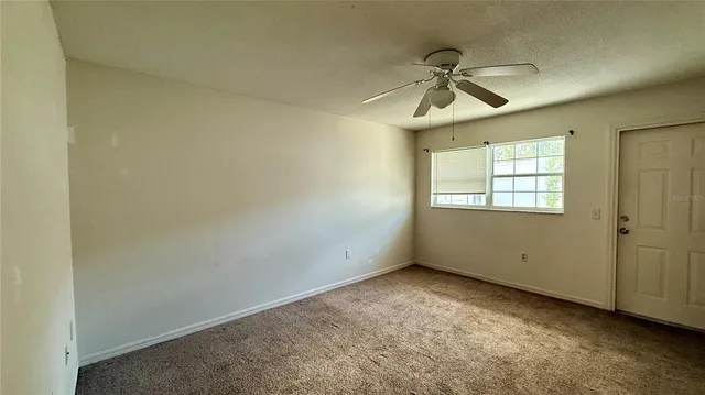 an empty room with a window and a ceiling fan