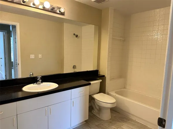 a bathroom with a granite countertop sink toilet a mirror and a bathtub