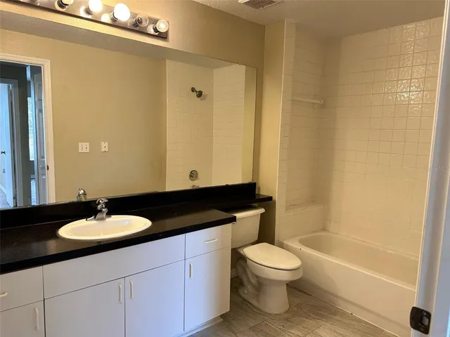 a bathroom with a granite countertop sink toilet a mirror and a bathtub