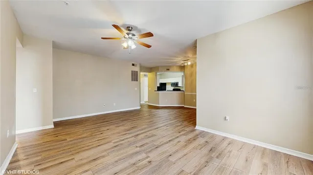 a view of empty room with wooden floor and fan