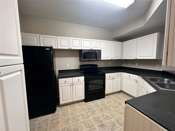 a kitchen with granite countertop a refrigerator and a stove top oven