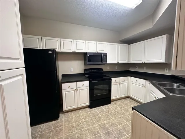 a kitchen with granite countertop a refrigerator and a stove top oven