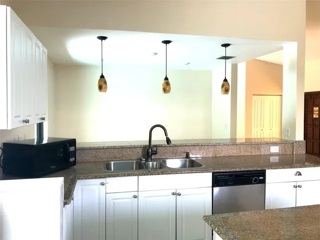 a kitchen with granite countertop a stove a sink a window and dining table