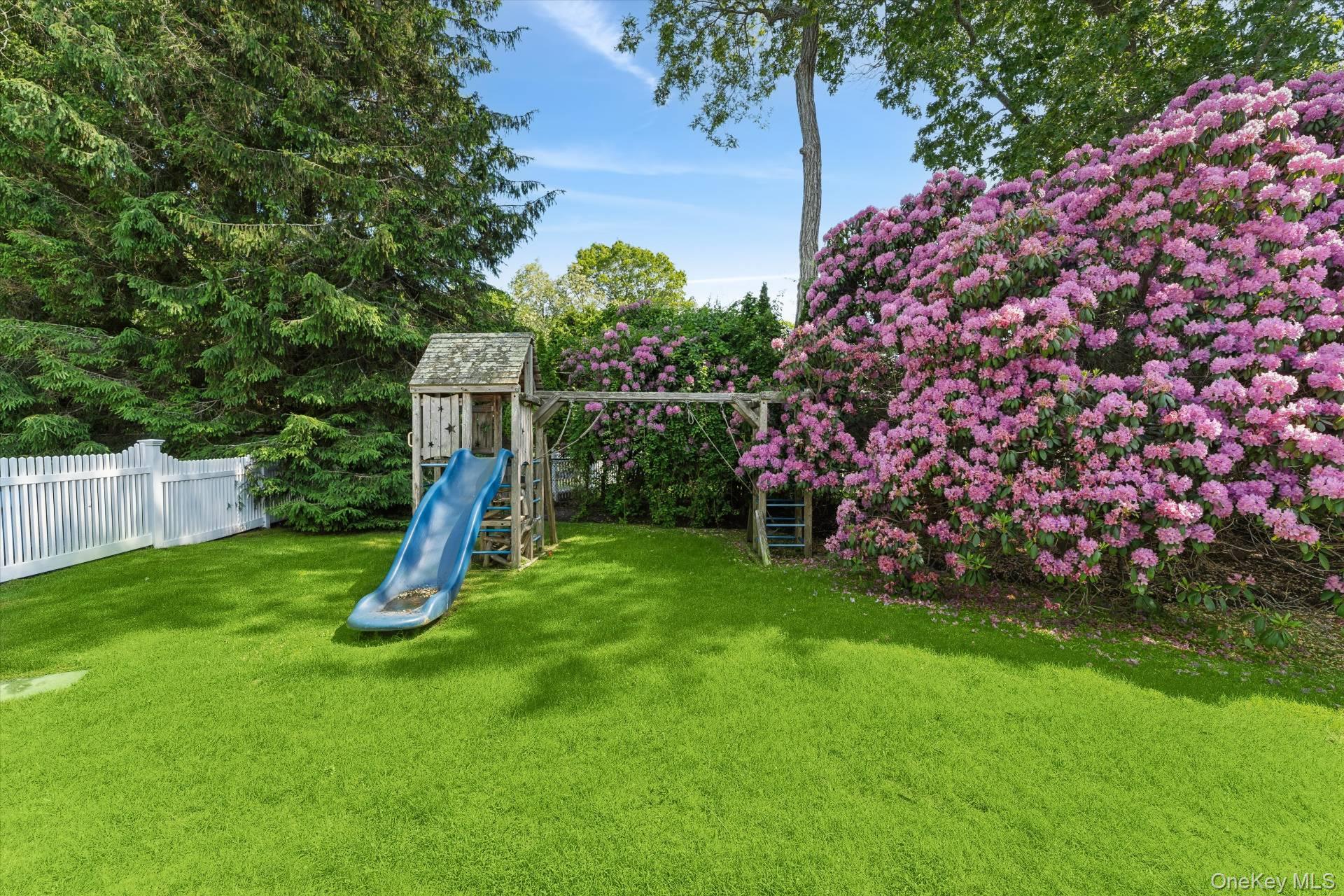 129 Oneck Lane Westhampton Beach, NY 11978 - Photo 28 of 32 a view of a backyard with a slide trees and wooden fence