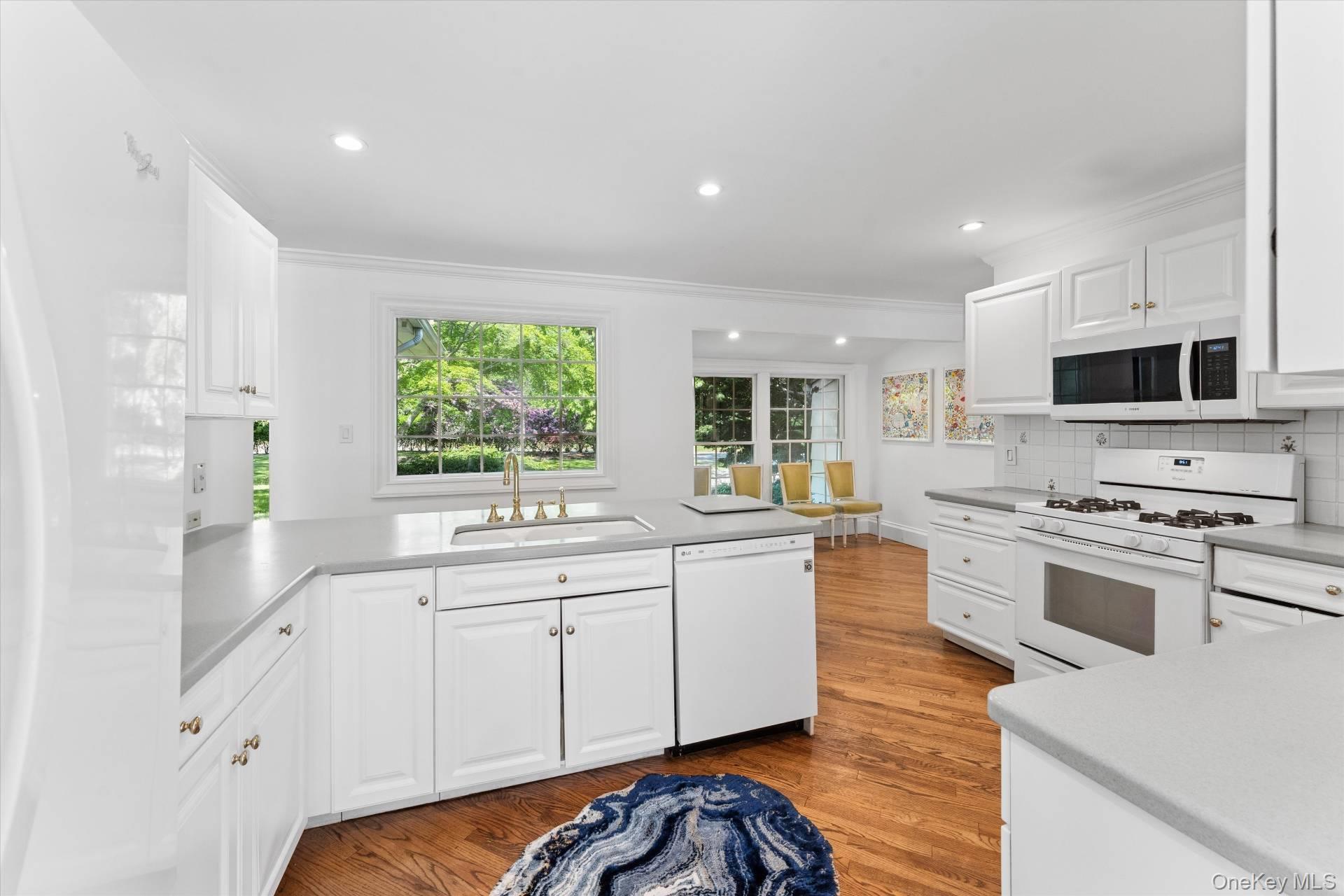 129 Oneck Lane Westhampton Beach, NY 11978 - Photo 5 of 32 a kitchen with stainless steel appliances white cabinets a sink a stove a microwave a refrigerator and cabinets