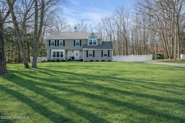 a view of a house next to a big yard and large trees
