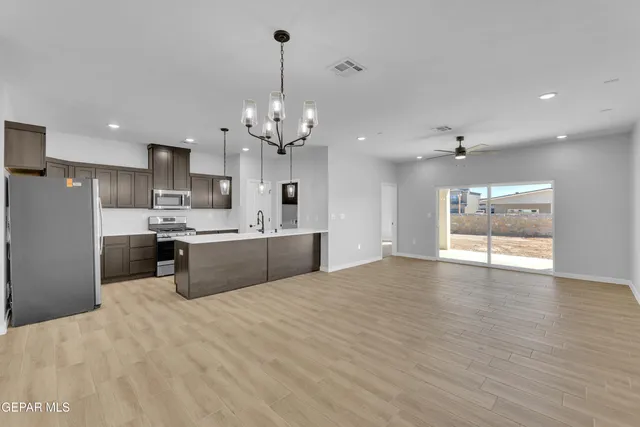 a large kitchen with kitchen island a sink dishwasher a refrigerator and a fireplace with wooden floor