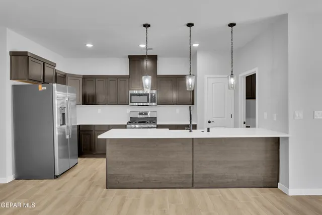 a large kitchen with stainless steel appliances kitchen island a refrigerator sink and wooden floor
