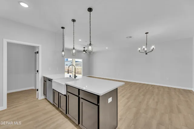 a room with a chandelier fan and wooden floor