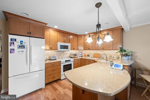 a kitchen with a refrigerator a stove a sink and a dining table with wooden floor