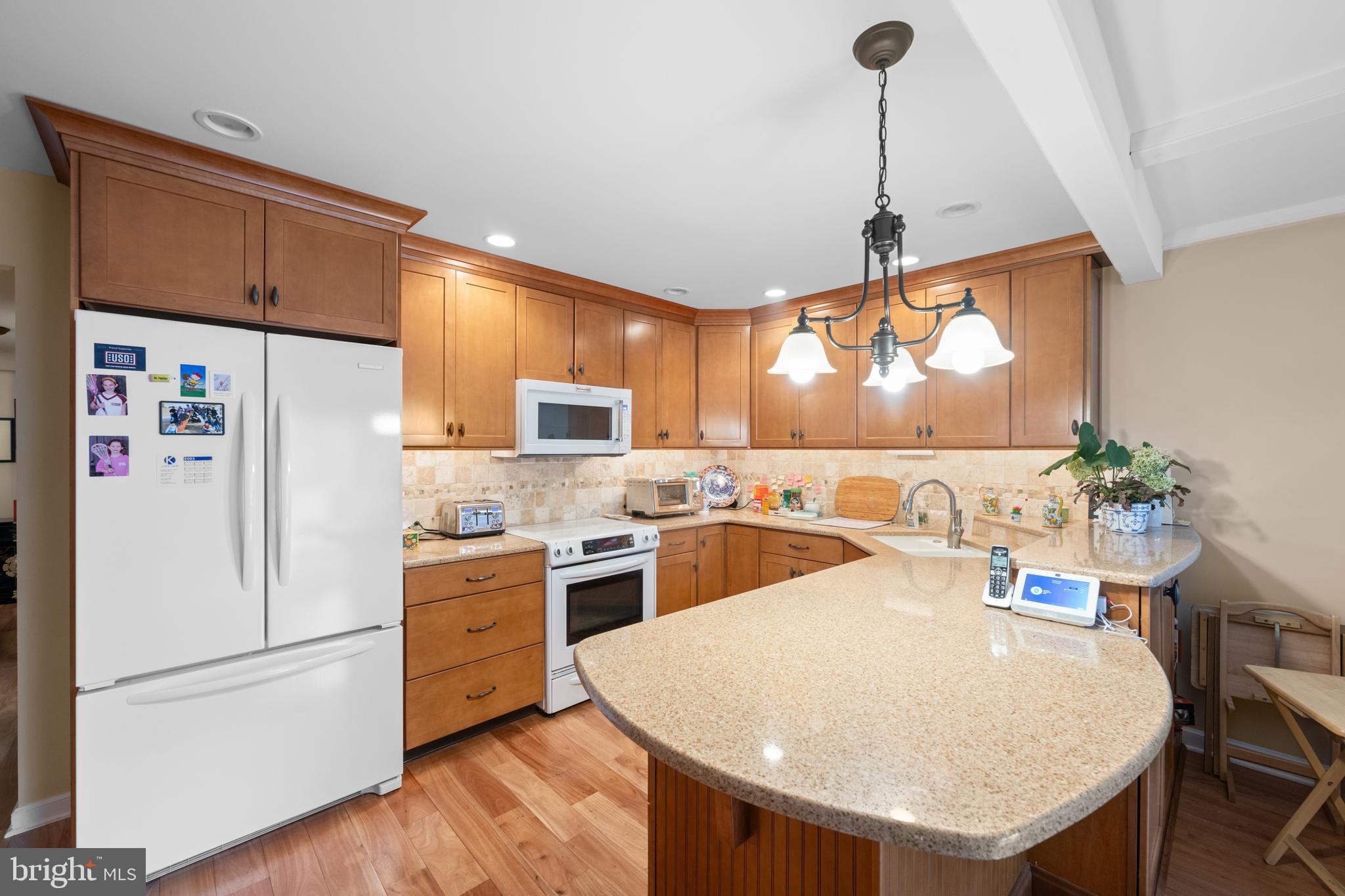 32 Manchester Court, Unit 32 Berwyn, PA 19312 - Photo 6 of 27 a kitchen with a refrigerator a stove a sink and a dining table with wooden floor