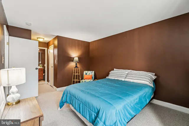 a bedroom with a bed and a lamp on dresser