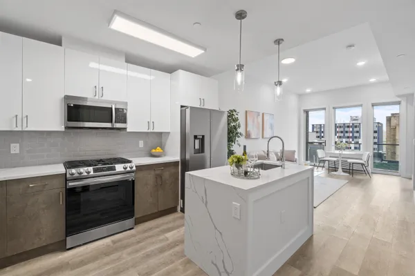a kitchen with stainless steel appliances kitchen island granite countertop a stove a sink a refrigerator and a white cabinets with wooden floor