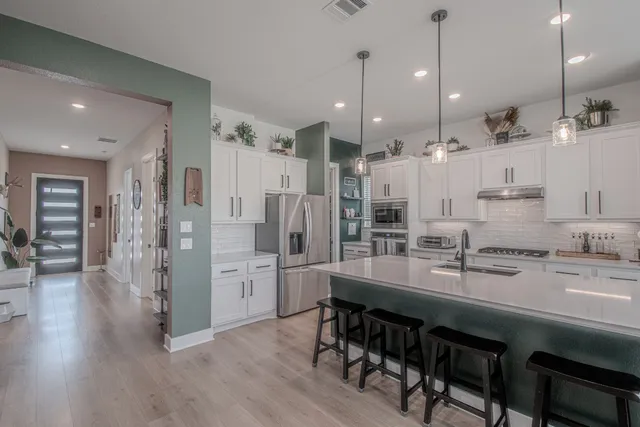 a large kitchen with stainless steel appliances kitchen island granite countertop a table chairs refrigerator and microwave