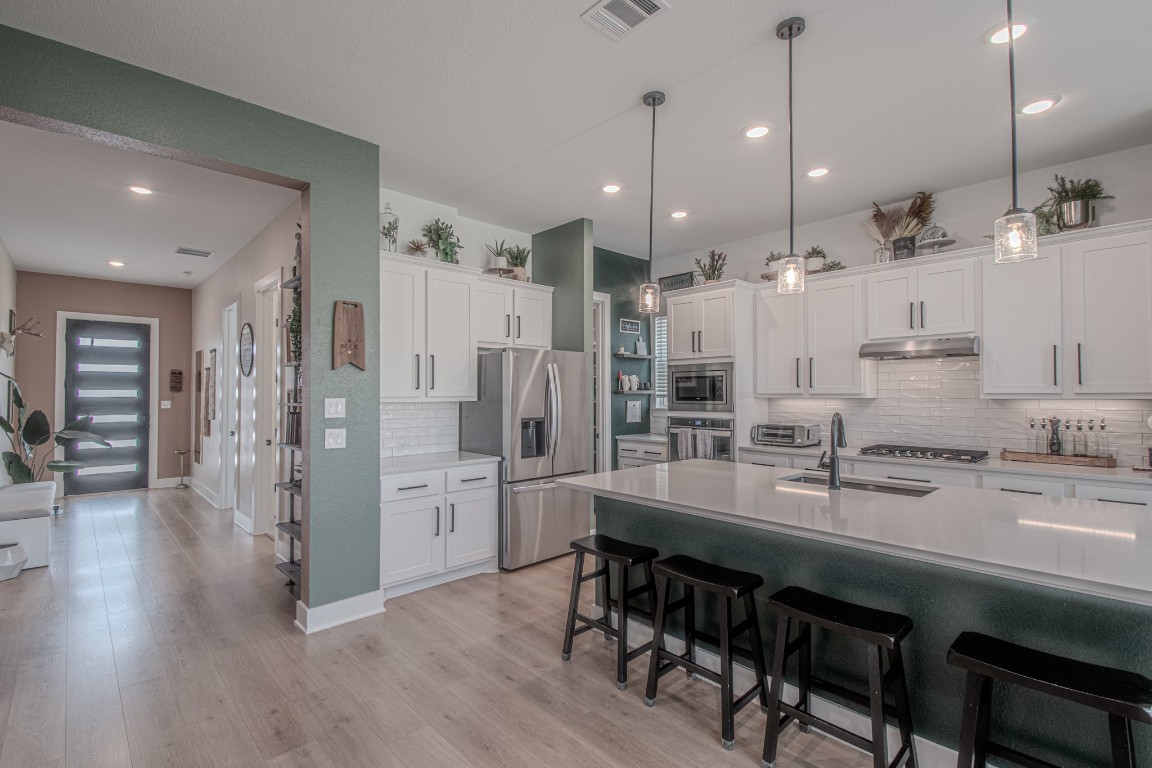 308 Millbend Road Georgetown, TX 78633 - Photo 6 of 40 a large kitchen with stainless steel appliances kitchen island granite countertop a table chairs refrigerator and microwave