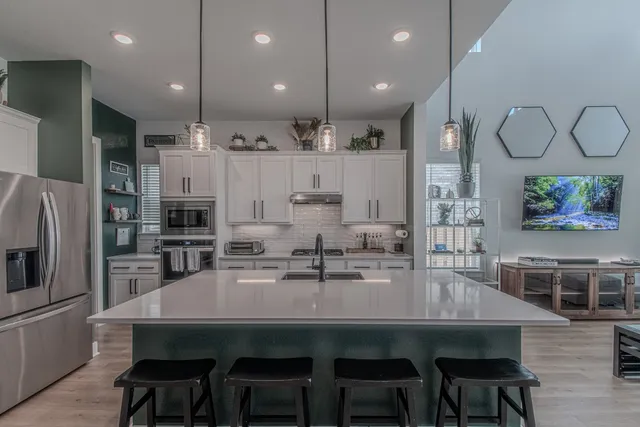 a kitchen with stainless steel appliances a dining table chairs refrigerator and microwave