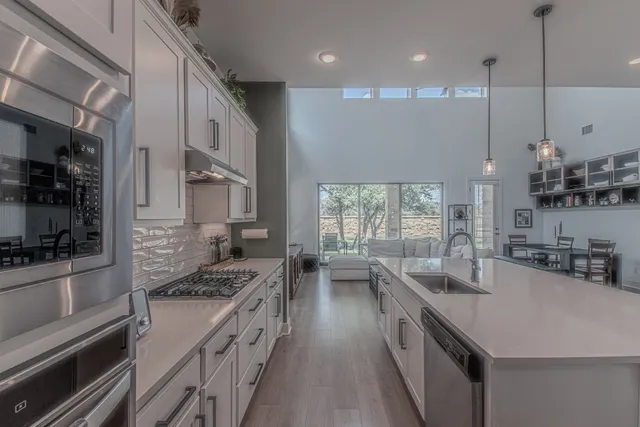 a kitchen with stainless steel appliances granite countertop a sink a stove and a refrigerator