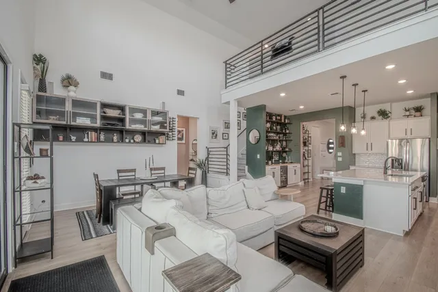 a living room with furniture a rug kitchen view and a table