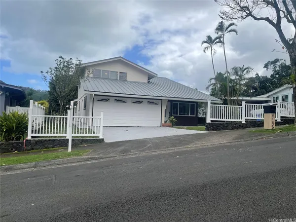 a front view of a house with a garden and trees