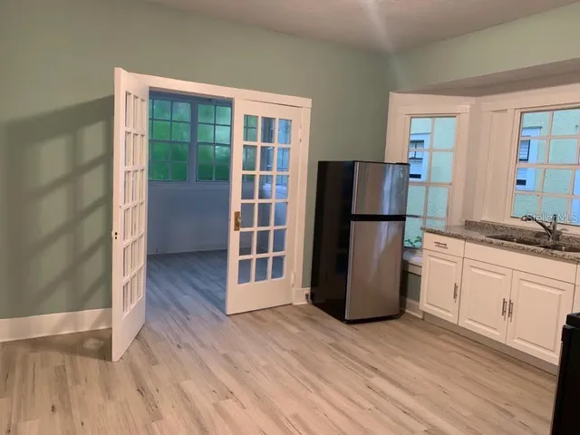 a kitchen with a refrigerator and wooden floor