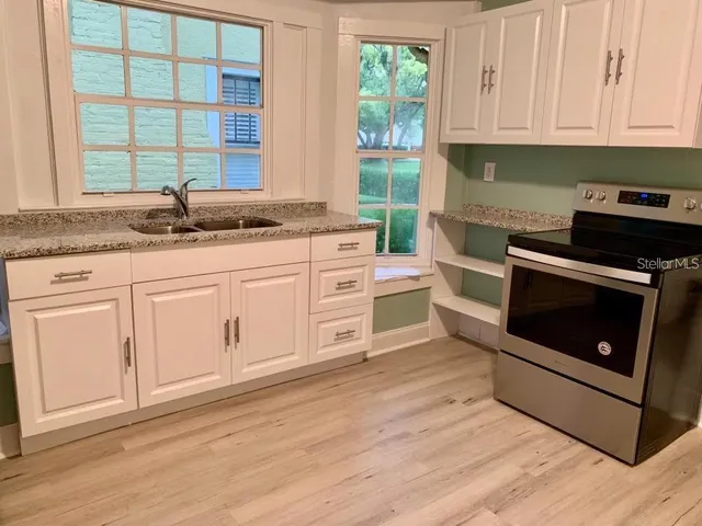 a kitchen with granite countertop white cabinets stainless steel appliances and a sink