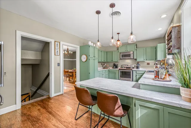 a kitchen with stainless steel appliances kitchen island granite countertop a table chairs and a refrigerator