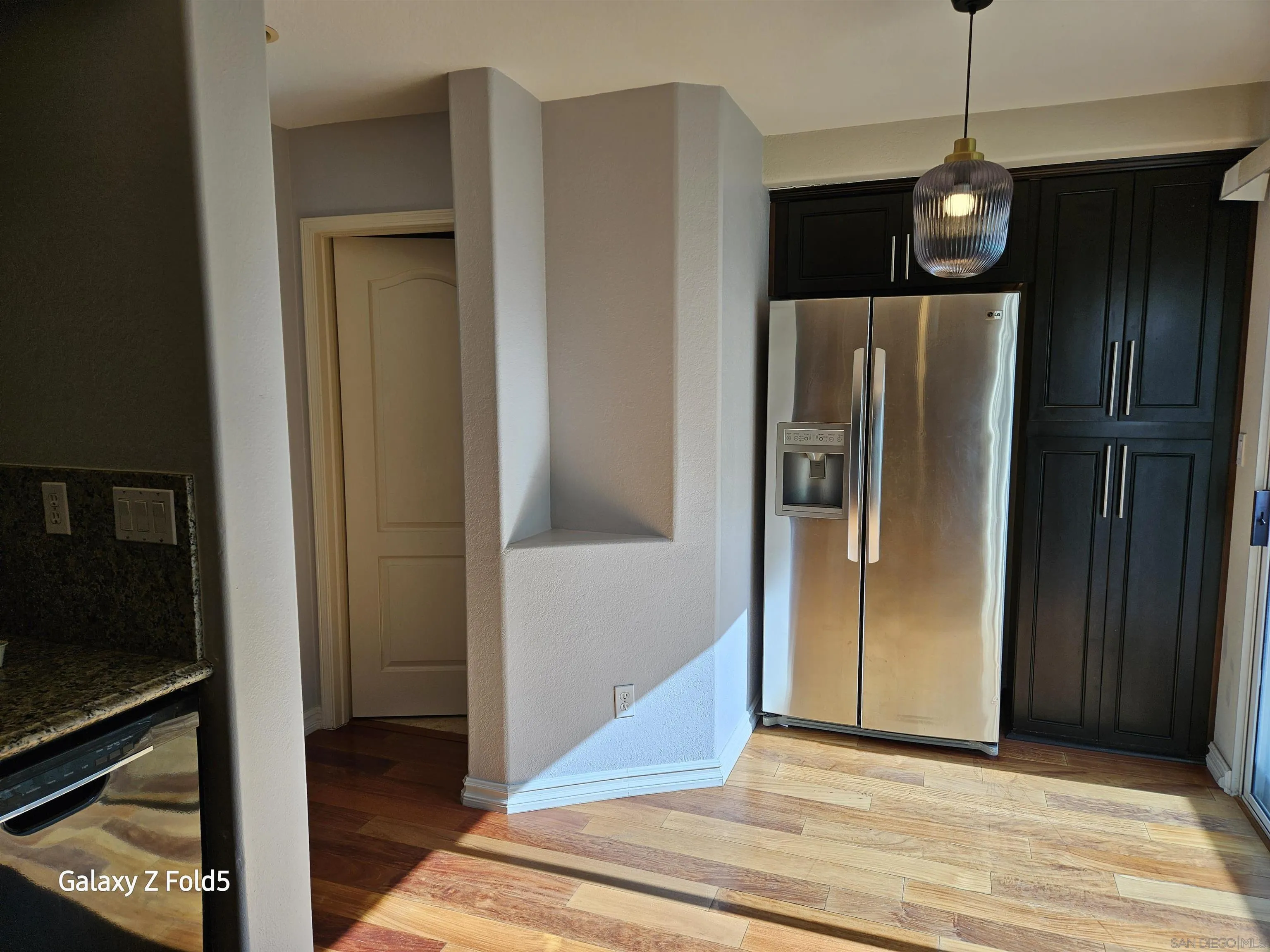 12980 Carmel Creek Road San Diego, CA 92130 - Photo 5 of 13 a view of a refrigerator in kitchen and an empty room with wooden floor