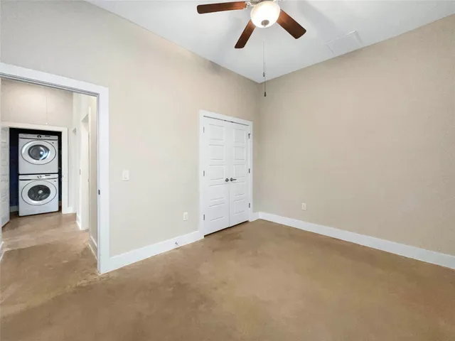 an empty room with ceiling fan and window